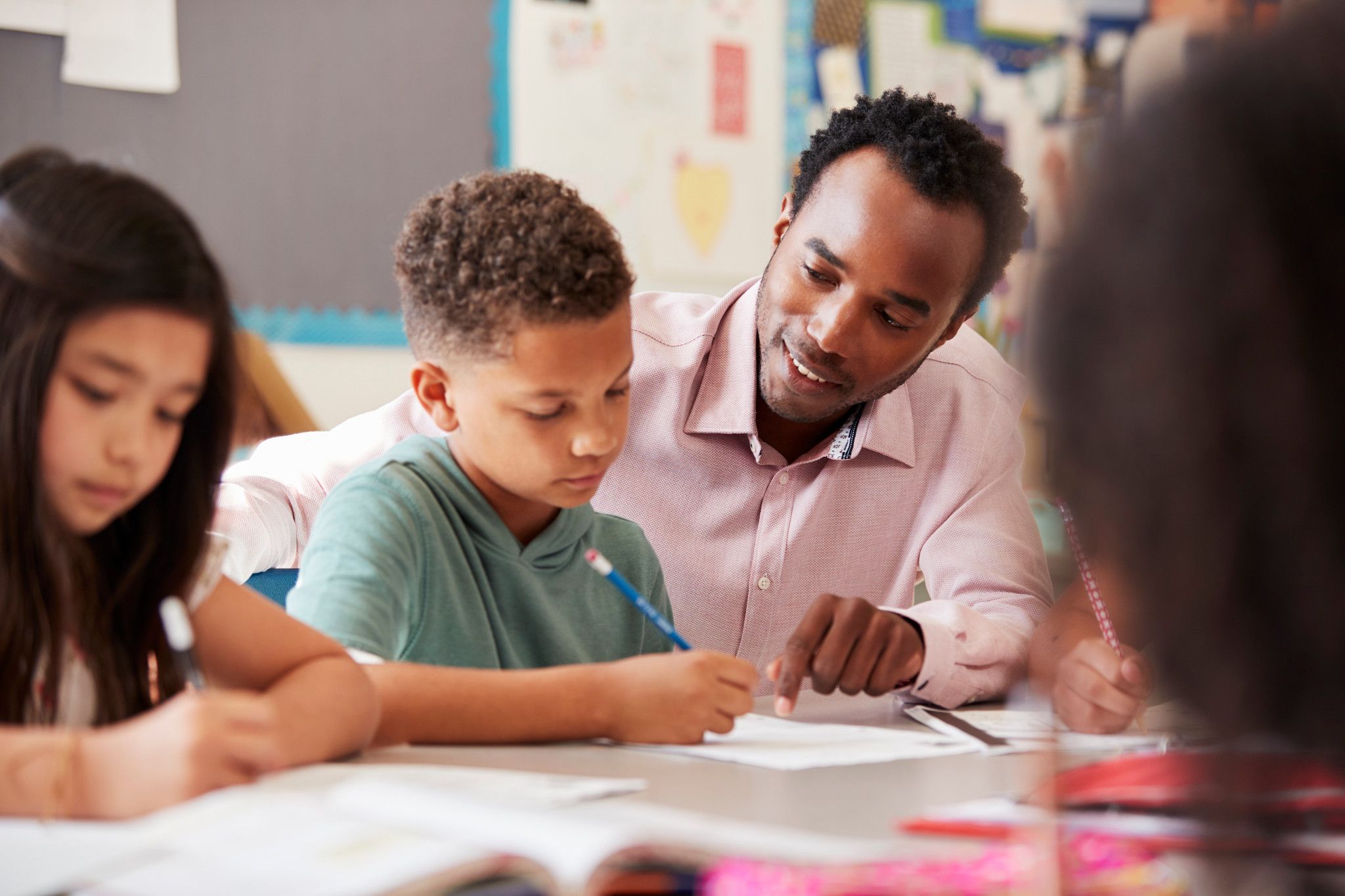 teacher with a teaching degree studying with elementary students at a table