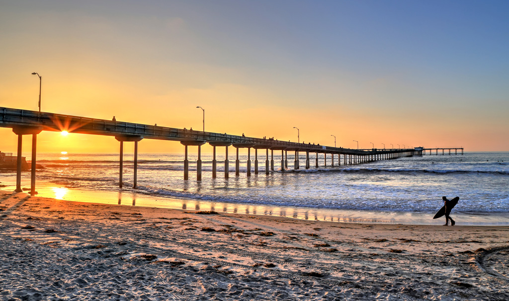 San Diego sunset and a man carrying surfboard