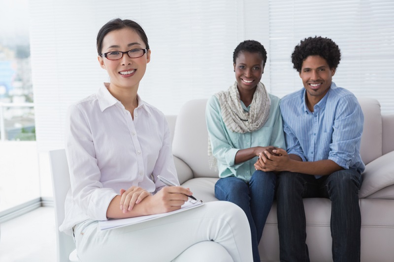A woman sitting on a couch with a couple of people