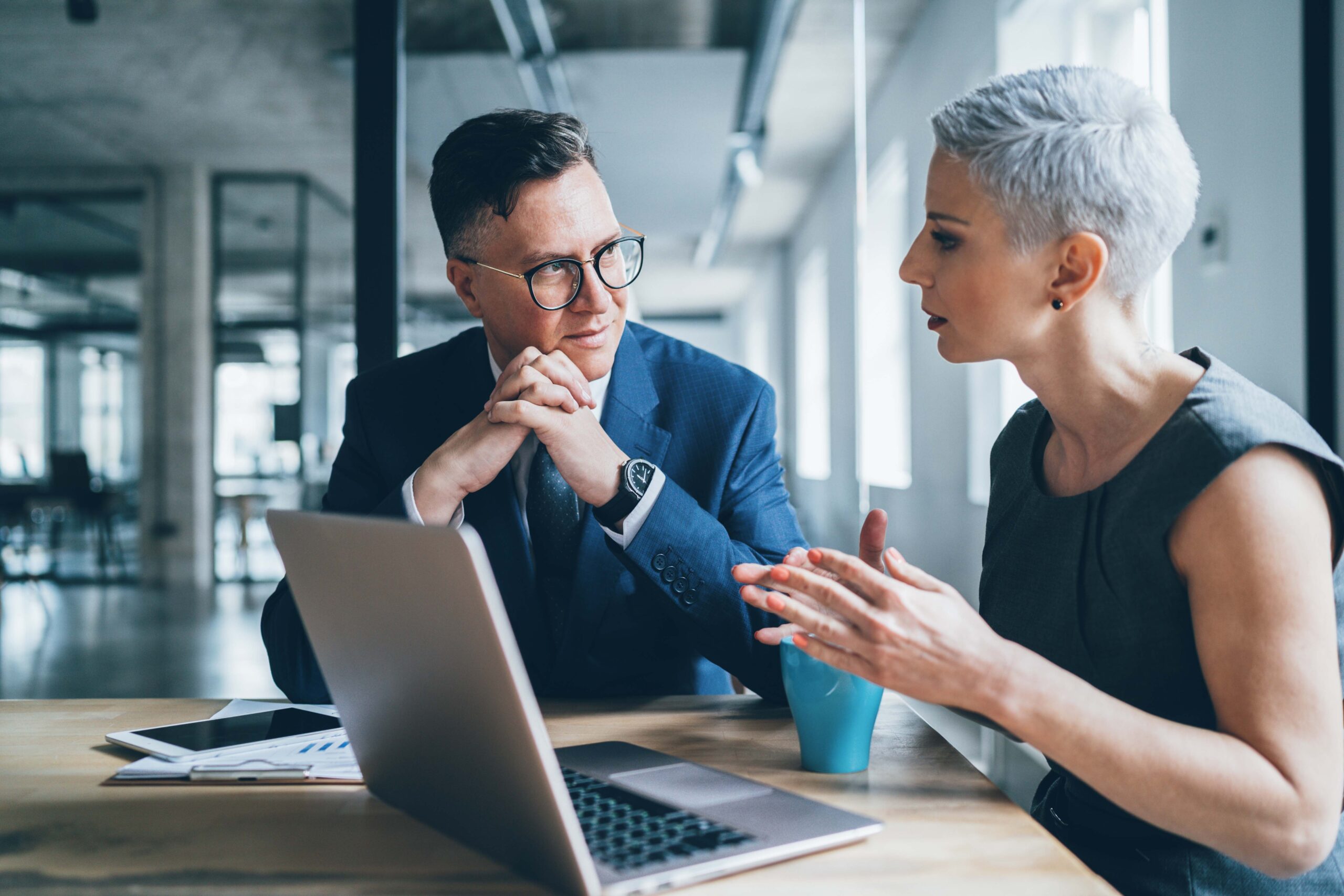 woman with a laptop in a meeting room talking with a man