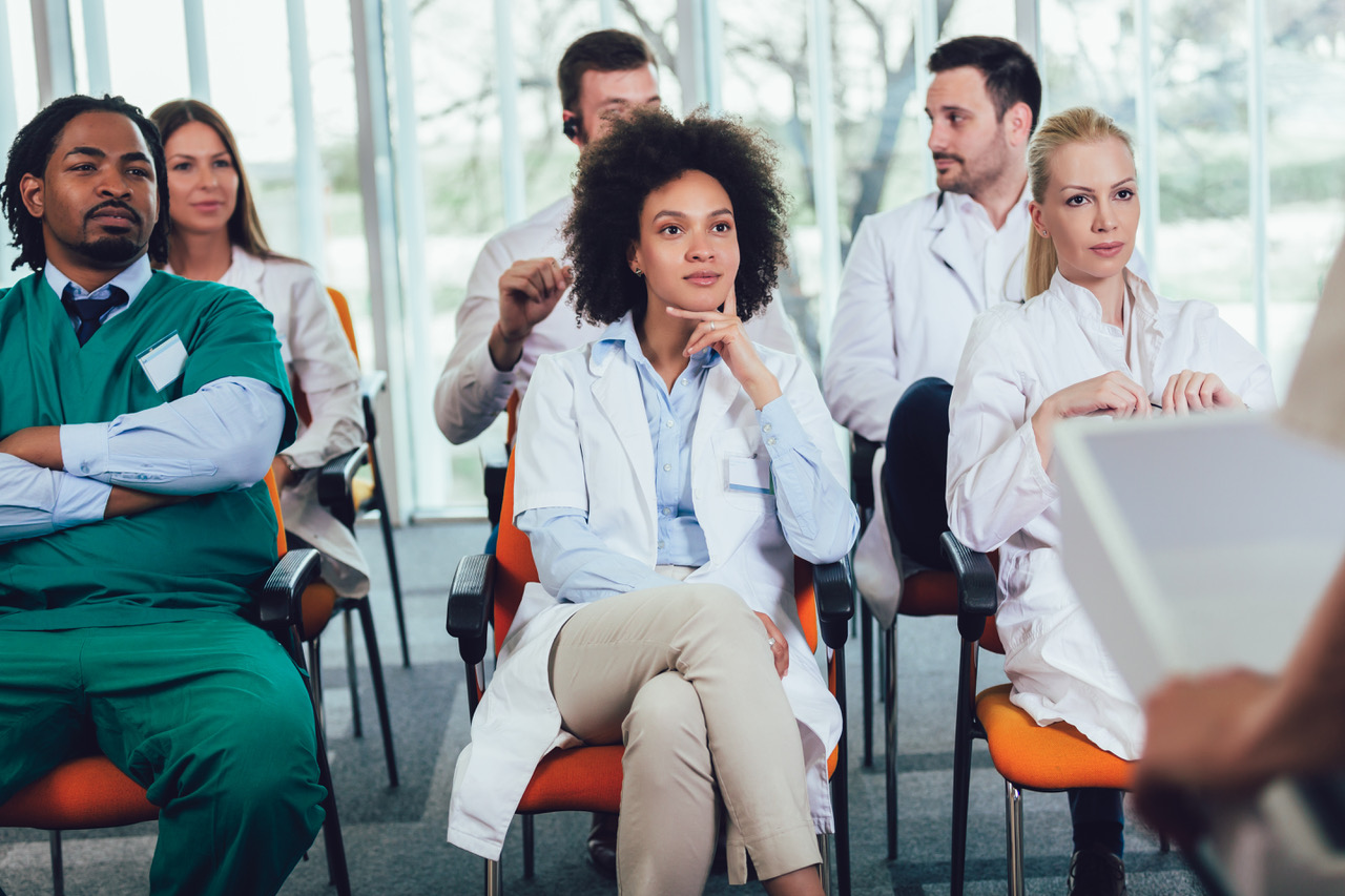 A group of people in white coats sitting in chairs