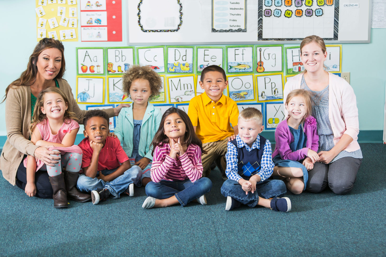two teacher interns posing for a class photo with their child students