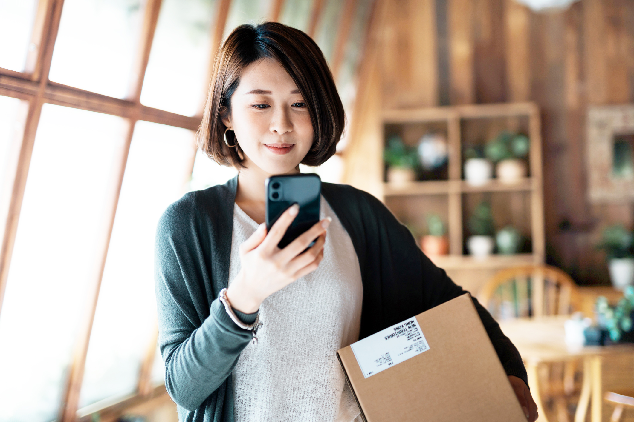 woman looking at phone holding package