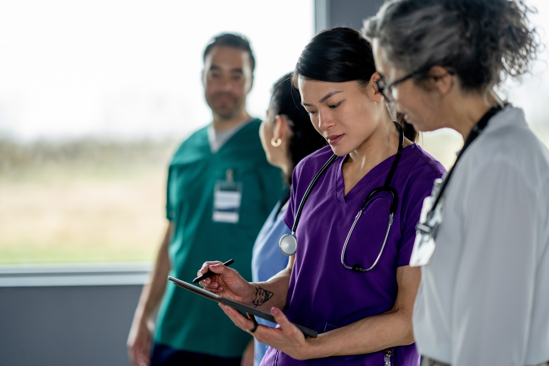 A group of people in scrubs looking at a tablet