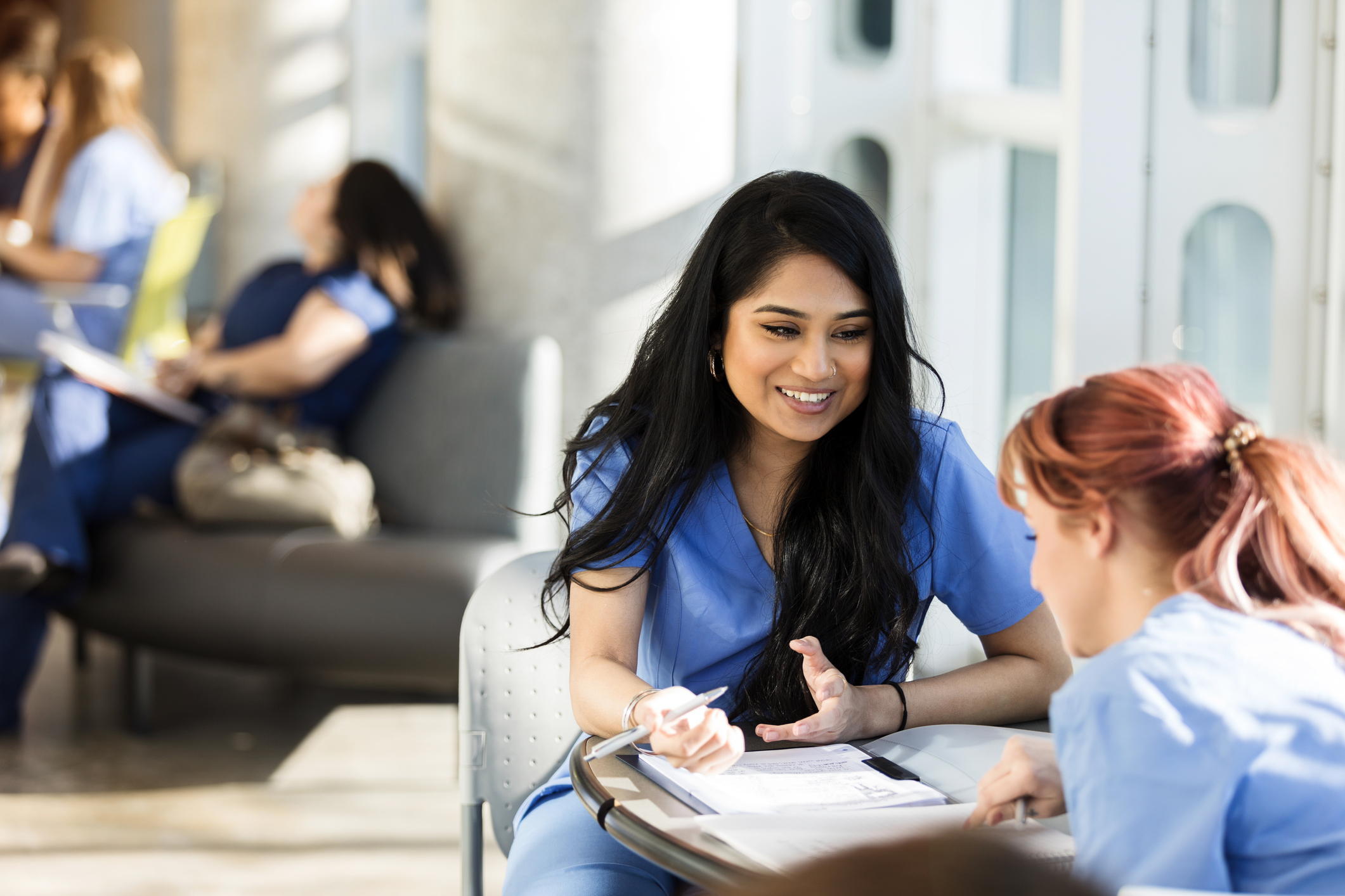 Nurse with notepad talking to another nurse