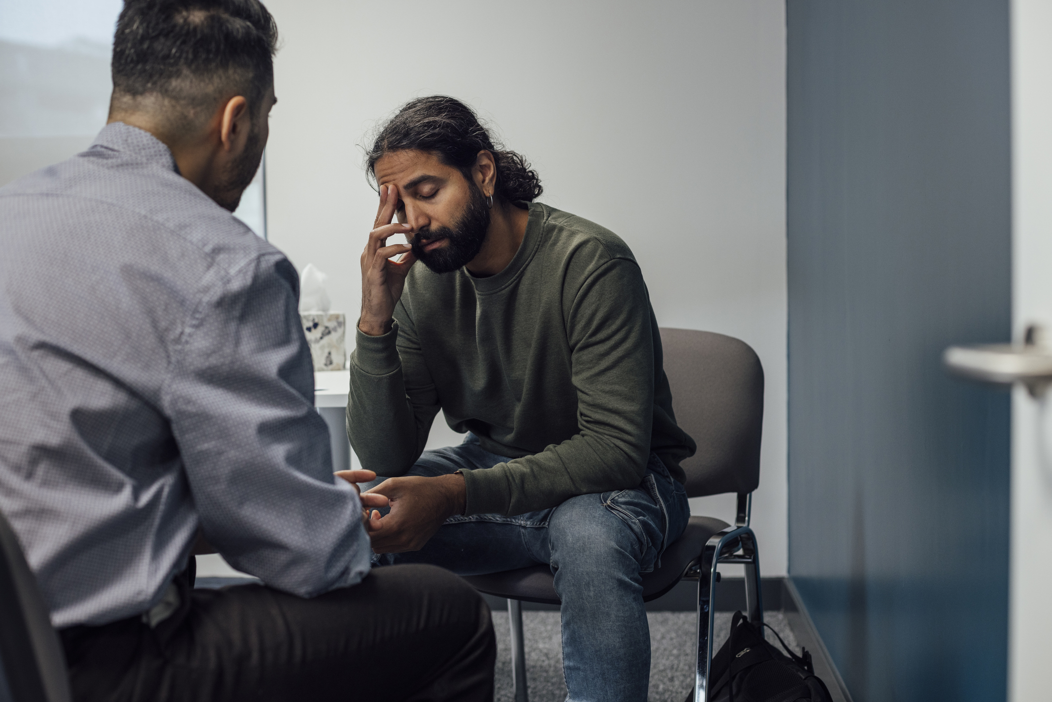 patient with hand on forehead talking with therapist